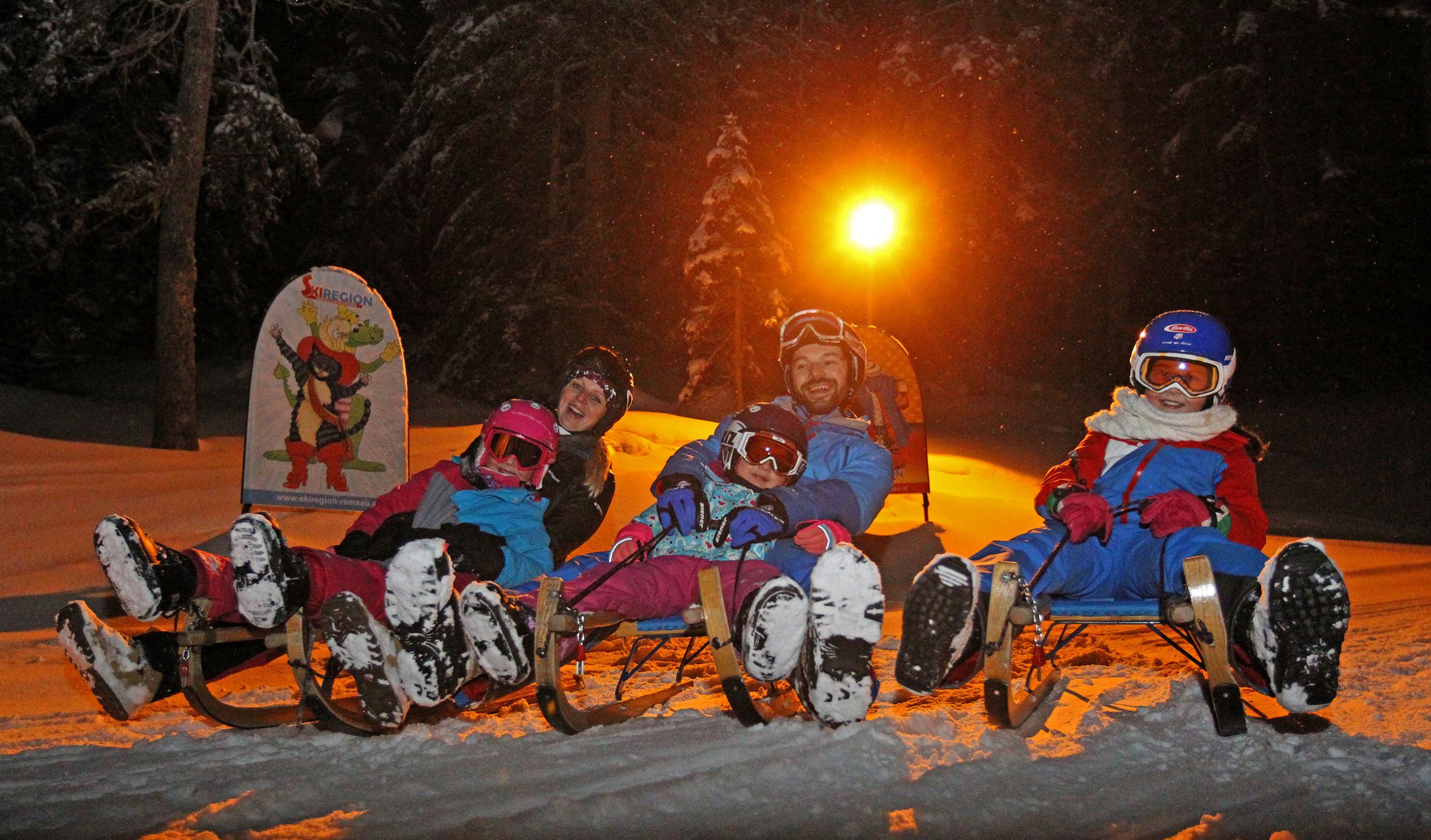 Familie mit Kindern hat Spaß beim Nachtrodeln am Rittisberg